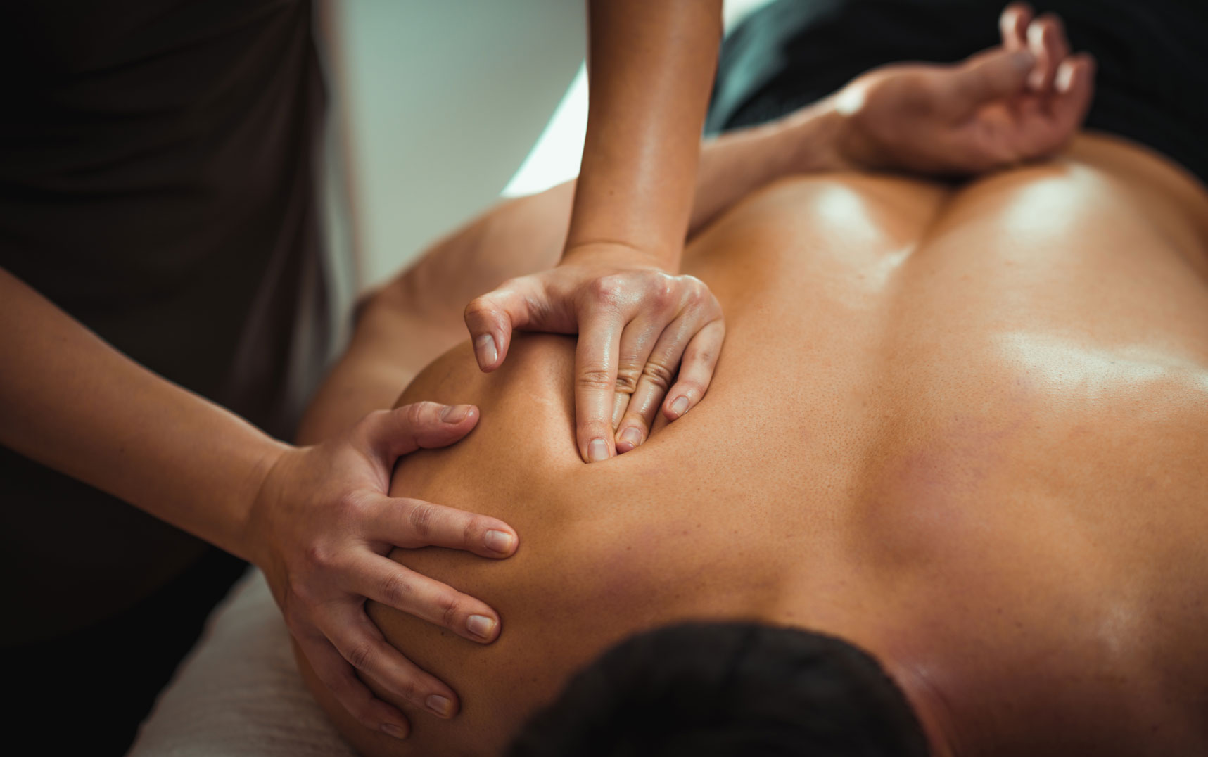 Therapeutische Massage – Rücken- und Schultermassage Tiefengewebsmassage an Rücken und Schulter eines liegenden Mannes – entspannende therapeutische Behandlung durch gezielten Fingerdruck.